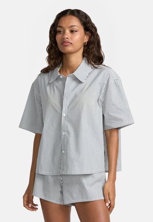 Chemise à manches courtes rayée en blanc et noir, avec un devant boutonné, un large col et une coupe décontractée et carrée. Short au motif assorti.