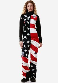 Tuta da sci con un motivo di stelle in bianco e nero e strisce rosse e bianche. Il materiale sembra essere sintetico; include loghi e dettagli con zip.