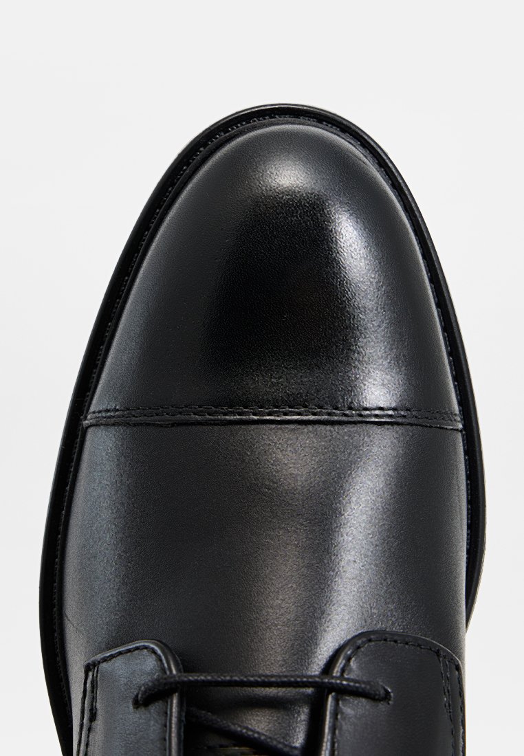 Czarne skórzane buty wyjściowe o gładkim wykończeniu, zaokrąglonym nosku i systemie sznurowania. Posiadają ozdobne przeszycia wzdłuż cholewki.