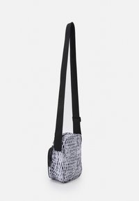 Černobílá crossbody taška s texturovaným designem zvířecího vzoru. Obsahuje dlouhý nastavitelný popruh a zipovou kapsu. Obdélníkový tvar.