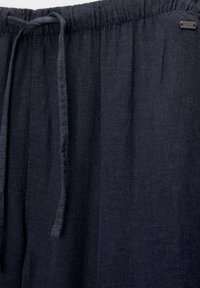 Granatowe lniane spodnie z gumką w talii i troczkiem, o subtelnej fakturze, idealne na codzienne noszenie.