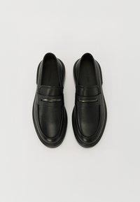 Mocassins en cuir noir avec une finition lisse, dotés d'une sangle avec un accent métallique décoratif et d'un design de bout arrondi.