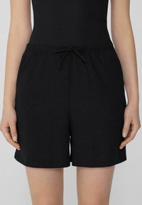 Pantaloni corti neri con vita elastica e coulisse, caratterizzati da un tessuto testurizzato e fessure laterali per maggiore comfort e stile.