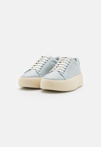 Baskets en cuir bleu clair avec une semelle blanche épaisse, bout rond et lacets blancs. Texture lisse, design minimaliste sans motifs.