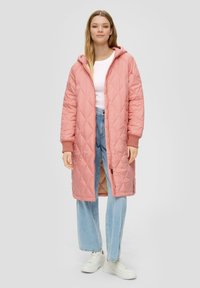 Gepolsterter pinker langer Mantel mit Kapuze, gerippten Bündchen und Reißverschluss vorne. Kombiniert mit hellblauen weit geschnittenen Jeans und weißen Turnschuhen.