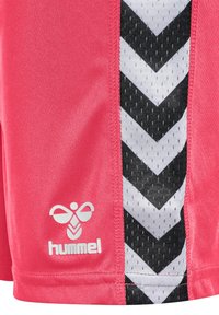 Röda sportshorts med svarta och vita chevron-mönstrade sidopaneler. Har en slät yta och en vit logotyp av märket "Hummel."