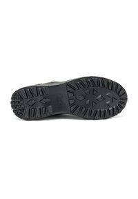 Suela de zapato de goma negra con un patrón de relieve profundo, que presenta formas angulares y en zigzag para una mejor tracción. Bordes reforzados para mayor durabilidad.