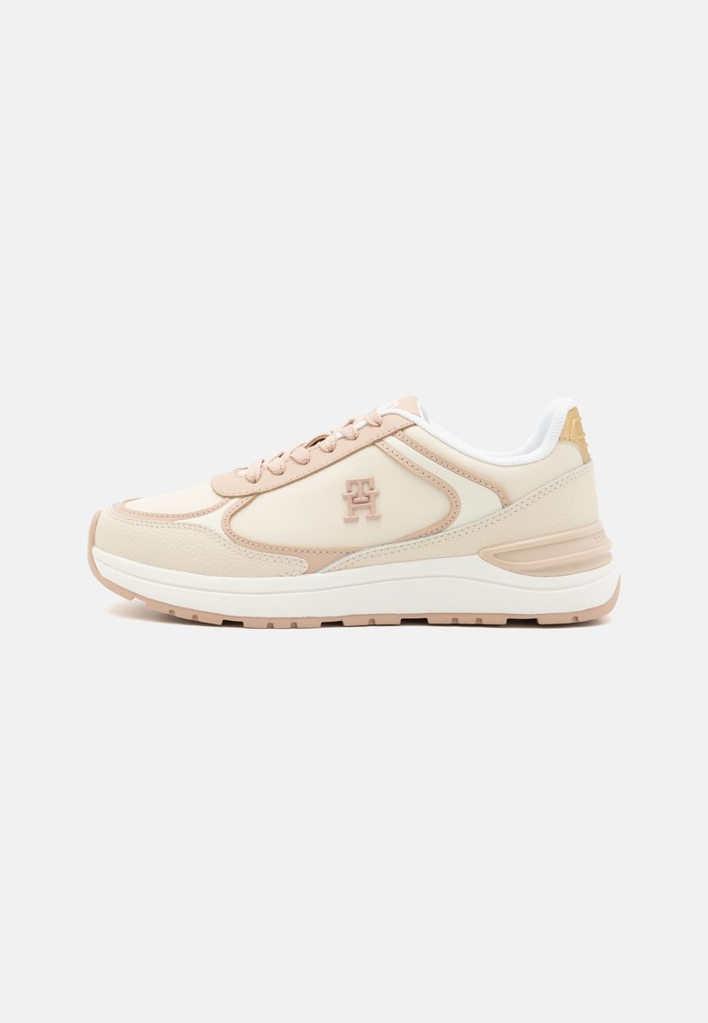 Beige and light pink athletic sneakers with a textured leather upper. Features a white midsole and logo accent on the side.