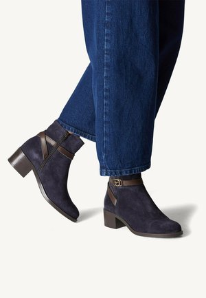 Stivaletti alla caviglia in suede blu navy con tacco a blocco, dotati di cerniera laterale e di una fascia in pelle marrone con dettaglio della fibbia circolare.