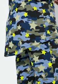 Kamouflage-mönstrat tyg med nyanser av blått, grönt, svart och gula stjärnor. Mjukt, icke-texturerat material med avslappnad passform.