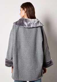 Cappotto in misto lana grigio con colletto e polsini in pelliccia grigia. Design a vestibilità ampia con maniche larghe e tessuto liscio.