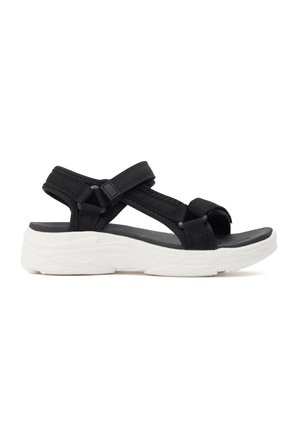 Sandalia negra de punta abierta con tiras ajustables y suela gruesa blanca acolchada diseñada para comodidad y uso casual.