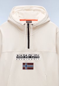 Kapuzensweatshirt in Creméfarbe mit schwarzem Reißverschluss, Kordeln, „NAPAPIJRI geographic“-Logo und einem rechteckigen Aufnäher mit der norwegischen Flagge auf der Vorderseite.