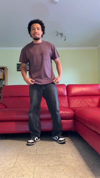 Smeđa pamučna majica s džeparom, u kombinaciji s plavim trapericama i crno-bijelim tenisicama. U pozadini je crveni kožni kauč.