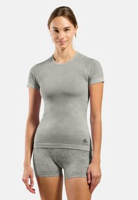 Light grey athletic top with short sleeves, textured fabric, and matching shorts with a subtle pattern. Features brand logo on the bottom.