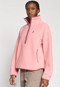 Ροζ fleece πουλόβερ με ψηλό γιακά, εμπρός μισό φερμουάρ και αντίθετη σκουρόχρωμη ροζ επένδυση. Διαθέτει πλαϊνές τσέπες και άνετη εφαρμογή.