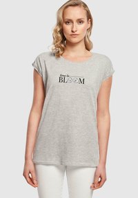 Šedé tričko s krátkým rukávem vyrobené z měkké bavlny, s kulatým výstřihem, s černým nápisem "čas kvést" ozdobeným květinovými akcenty.