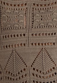 Gebreide stof in taupe met intrigerende patronen, waaronder vierkanten en geometrische vormen, verbeterd met gaten en textuurdetails.