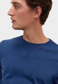 Blå crewneck sweatshirt med en glat tekstur, der har en syet detalje ved halsudskæringen og en klassisk pasform.