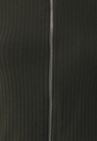 Black ribbed fabric garment featuring a central metal zipper closure with silver hardware. The texture is smooth and slightly stretchy.