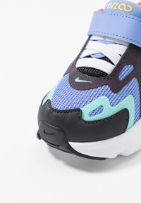 Nike-sneakers med övre del i lila mesh, inslag av teal och svart, vadderad krage och vit sula. Central snörningssystem med rem.