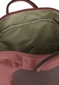Interior de mochila de tela roja y verde con cierre de cremallera; presenta múltiples compartimentos y una textura suave y mate.