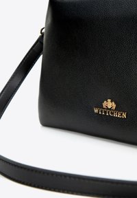 Czarna skórzana torba na ramię z tłoczonym wzorem, z złotym logo "Wittchen" i cienkim paskiem. Gładkie wykończenie z delikatnym połyskiem.