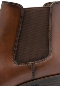 Stivale in pelle marrone con un pannello elastico marrone scuro, punta arrotondata, cuciture visibili e una finitura testurizzata sul materiale elastico.