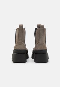 Botines de ante grises con plataformas de goma negras, paneles laterales elásticos y lengüetas en la parte trasera. Acabado texturizado y costuras en contraste.