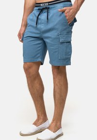 Shorts cargo bleus en coton avec une taille élastique et un cordon de serrage, dotés de poches latérales et d'une poche à rabat sur la cuisse.