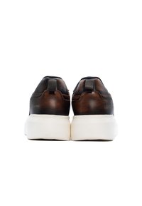 Hnedé kožené tenisky s textúrovaným povrchom, bielou gumovou podrážkou a úchytkami na zadnej strane. Minimalistické logo pri päte.