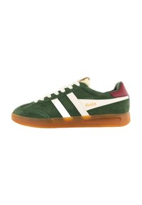 Zapatilla de ante verde con rayas blancas, suela de goma marrón y acento burdeos en el talón. Presenta cordones y un pequeño logo en el lateral.