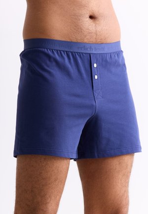 Männlicher Oberkörper und obere Beine mit blauen Baumwoll-Boxershorts mit elastischem Bund und zwei weißen Knöpfen am vorderen Verschluss.