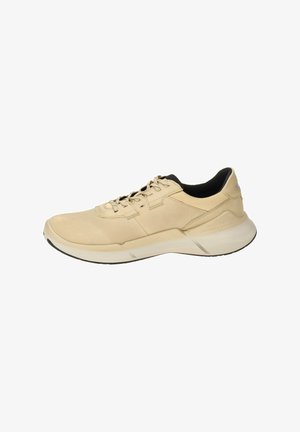 Light beige athletic shoe with a smooth leather and mesh upper, black sockliner, lace-up closure, and a thick white sole with black accents.