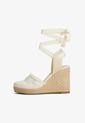 Beige Keil-Espadrille-Sandale mit gewebter Strohlaufsohle, Stoffoberteil und langen Wickelbändern für den Knöchel.
