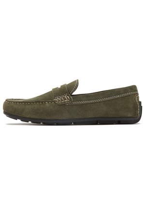 Mocasines de ante verde con un estilo mocasín, que presentan acentos de costura y una suela de goma negra. La vista lateral destaca la punta redondeada y la ausencia de cordones.
