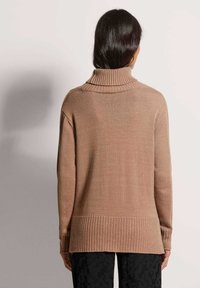 Kamel-farbener Strickpullover mit hohem Rippenkragen, lockerem Schnitt und geripptem Saum, ausgestattet mit langen Ärmeln und einem leicht längeren Design hinten.