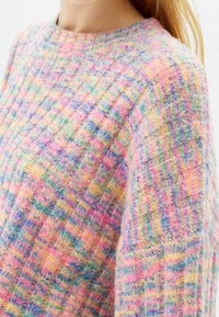 Pull en laine multicolore avec un motif à carreaux dans des tons roses, bleus et jaunes, doté d'un col rond et d'un tricot texturé.