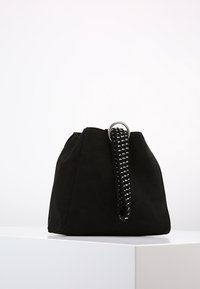 Svart mockaväsk med en strukturerad form, som har en slät yta och en flätad rem med en metallring som accent.