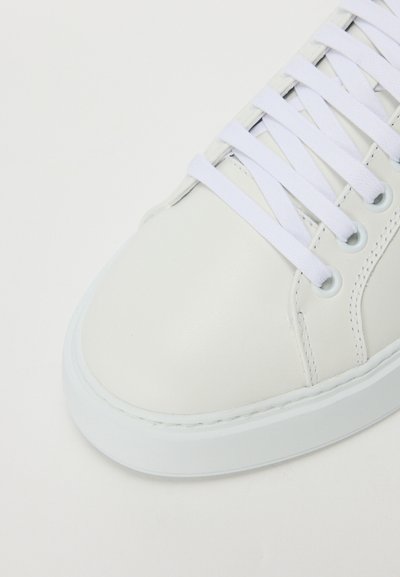 Adidași din piele albă cu vârf rotunjit, talpă plată și sistem de șireturi albă. Prezintă cusături minime și o textură netedă.