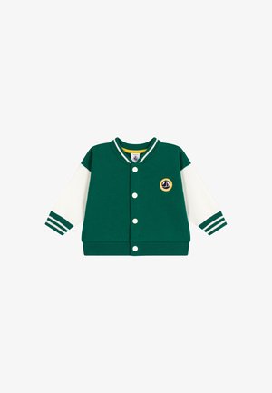 Grønn hettejakke med hvite ermer, ribbede mansjetter og en rund lapp. Har knappestenging og stripet detalj på kragen.