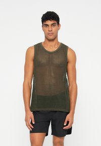 Top a rete verde oliva con scollatura rotonda, caratterizzato da una vestibilità ampia e un tessuto testurizzato. Abbinato a pantaloni corti neri.