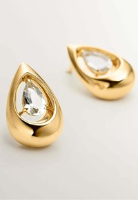 Pendientes en forma de lágrima de tono dorado con una piedra transparente facetada enmarcada en un diseño abierto, que muestra una superficie lisa y pulida y un diseño moderno.