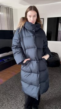 Puffer coat made of dark navy fabric, featuring a high collar, large pockets, and a quilted pattern with visible stitching.