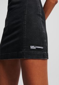 Čierna riflová mini sukňa s obtiahnutým strihom, viditeľným šitím a vyšitým logom "KARL LAGERFELD JEANS" na boku.
