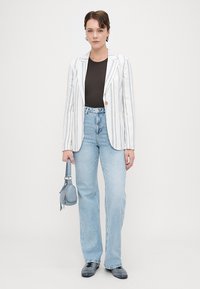 Randig kavaj i vitt och blått, svart topp, ljus tvättade utsvängda jeans, liten blå handväska, svarta skor. Slätt tyg, skräddarsydd passform.