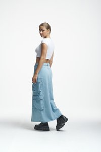 Svetlo modra denim krila s cargo žepi, v kombinaciji z oprijetim belim kratkim topom s kratkimi rokavi. Model nosi črne škornje z debelim podplatom.