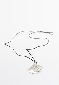 Collana con pendente in argento di forma astratta, appesa a un cordino nero. Il pendente presenta una superficie liscia e riflettente.