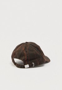 Σκούφος μπέιζμπολ σκούρου καφέ με διχρωμία σκουριάς, λουρί με μεταλλική πόρπη στο πίσω μέρος, τοποθετημένος σε λευκή επιφάνεια.