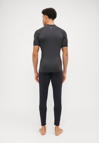 Zwarte sportieve rash guard met korte mouwen en strakke zwarte legging. Glad, rekbaar materiaal met een minimalistisch design.